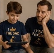 A boy holds a tablet while his father in a NoSay tee rests his head in his hand.